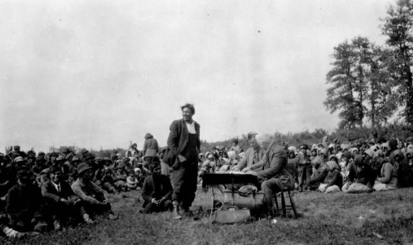 Chief Samson Beardy standing and Commissionners Cain and Awrey seated at the table during the negociations of Treaty 9 payments. From left to right, front row: Simeon and Jeremiah McKay, Isaac Barkman. At the left of Chief Samson, Johnny Anderson