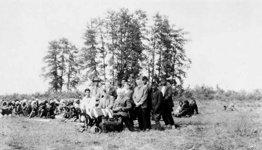 Government officials and Indians who signed Treaty 9. L. to r. (seated): K. Bayly, interpreter, and Commissioners Walter C. Cain and H.N. Awrey; (standing): Dr. Bell, Mrs. Garret and Rev. Garret and the Indians